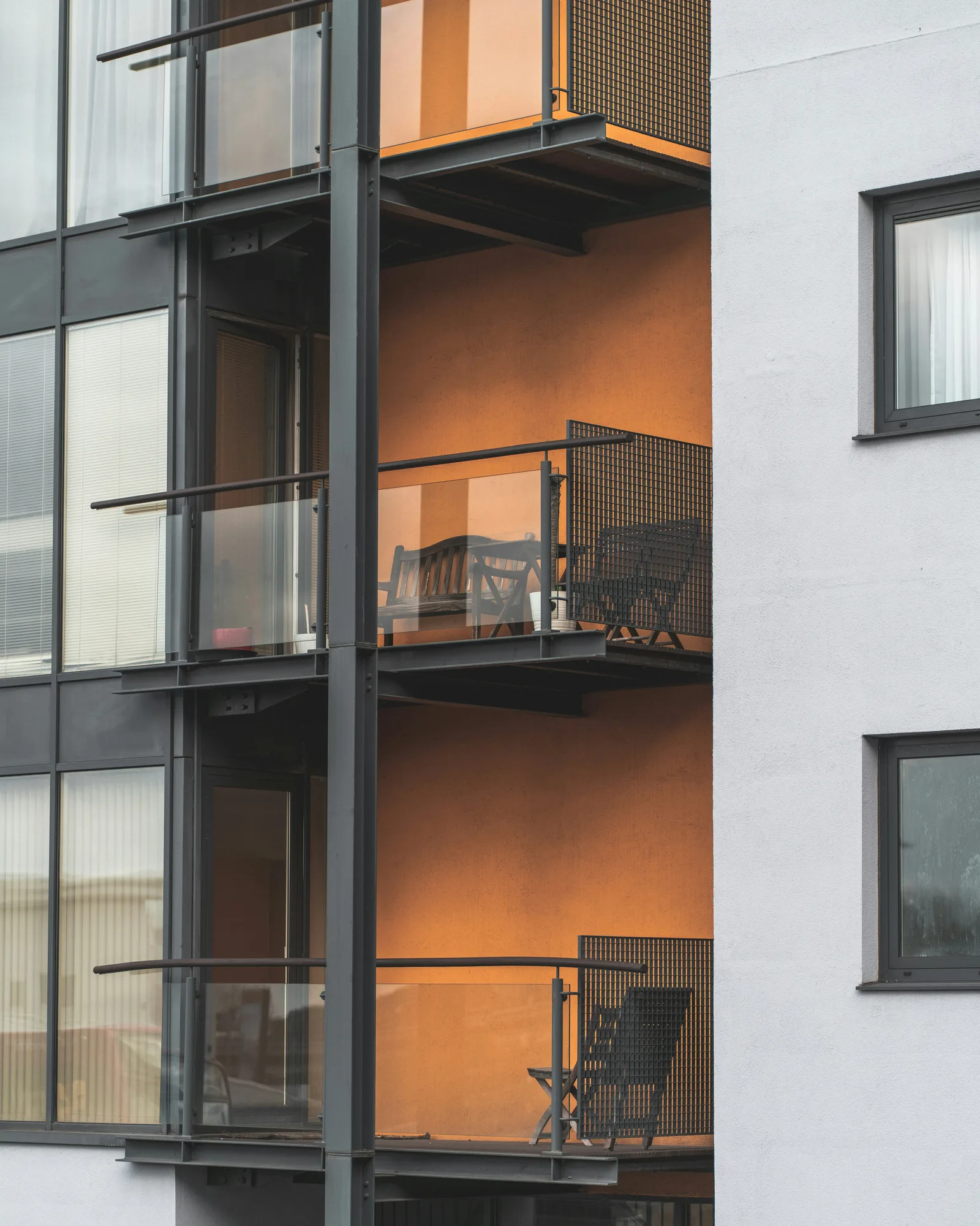 Mehrgeschossiges Wohngebäude mit orangefarbener Fassade und Balkonen mit Metallgeländer